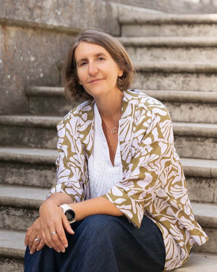 Anna Blair, cancer coach, sitting on sunlit stone steps