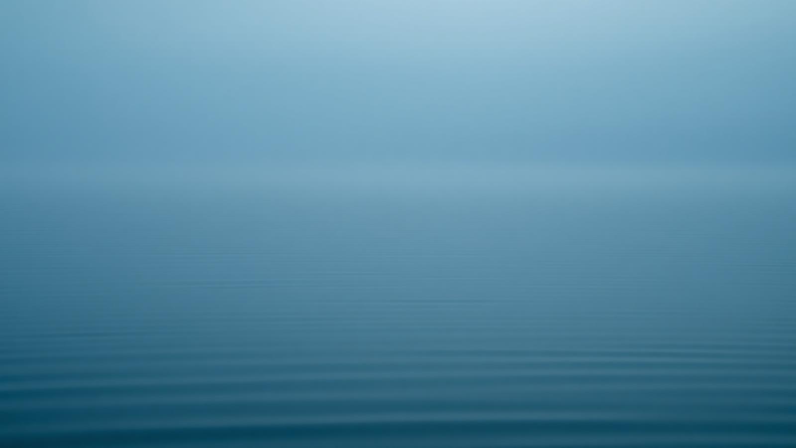 Still water at dawn in deep teal and misty grey tones